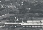 Pohled na komíny od západu z mostu přeložky silnice II/150 nad dnešní nádrží. Přední komín. Fotografii poskytl OÚ Dolní Kralovice