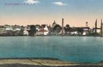 Dobová pohlednice - nedatováno. Pohled z břehu Zámeckého rybníka na nynější stavebniny.