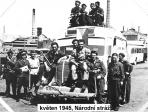 Foto z roku 1945 s Národní stráží, jejíč členové se rekrutovali i z řad zaměstnanců sklárny, nižší z komínů tehdy ještě neubouraný